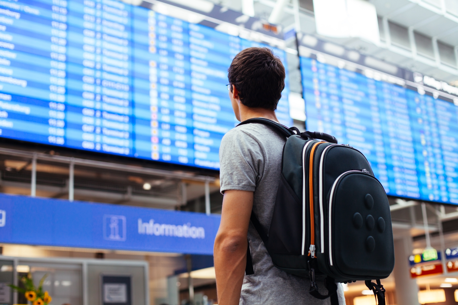 mees seisab seljakotiga lennujaama ekraanide ees